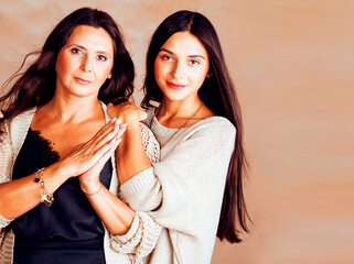cute pretty teen daughter with mature mother hugging, fashion style brunette makeup together, warm colors