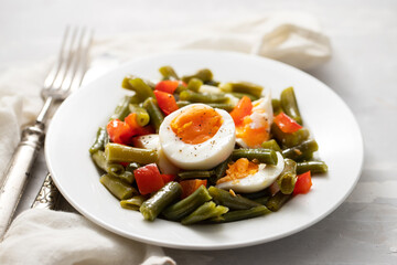 salad green beans, pepper and boiled eggs on white plate