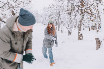 Fototapeta na wymiar Couple playing with snow and girlfriend throwing a ball in winter holidays