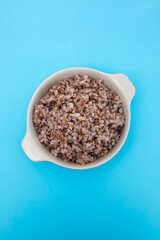 boiled buckwheat in small white bowl on blue