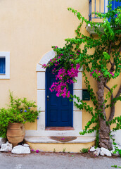 Fototapeta na wymiar Colorful blue door of traditional greek house with yellow walls at Asos village. Assos peninsula famous and extremely popular travel destination in Cephalonia, Greece, Europe