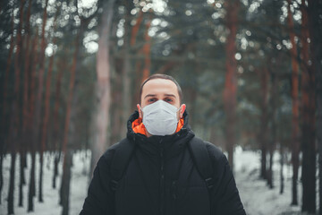 Fototapeta na wymiar Attractive Short-haired Man in a medical mask Walks in the forest.