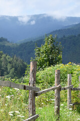 Old wooden fence on the background of the mountain landscape. Nice view of the forest and mountains.