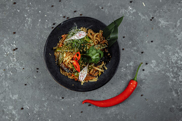 Stir-fried noodles and vegetables, in black bowl. Delicious, nutritious Asian food
