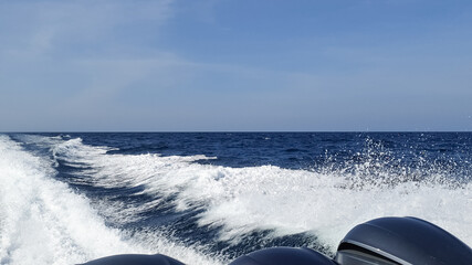 Sea wake trail behind a speed boat with waves, foam, bubbles on the ocean water surface with clear...