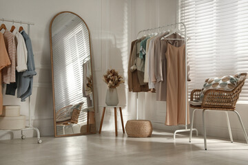 Modern dressing room interior with stylish clothes and beautiful dry flowers