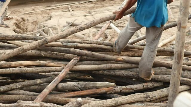  worker removing thin logs from the messy stack