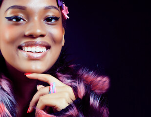 young pretty african american woman in spotted fur coat and flowers on head smiling on black background, fashion people concept