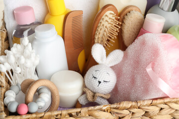 Obraz na płótnie Canvas Wicker basket full of different baby cosmetic products, bathing accessories and toys, closeup