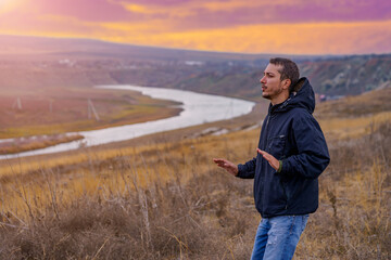 man tourist or a hiker in a windbreaker is engaged in spiritual practices at dawn. Background with copy space for text © Iurii Gagarin