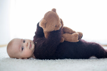 Little cute baby boy, dressed in handmade knitted brown teddy bear overall