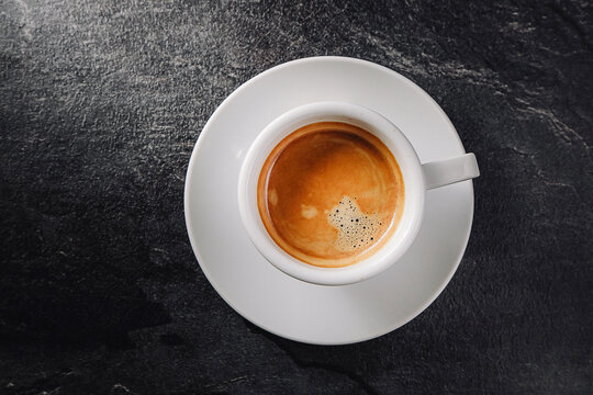 A cup of aromatic coffee on a dark table. View from above