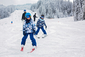 Fototapeta na wymiar Cute preschool children, skiing in Austrian winter resort on a clear day, wintertime