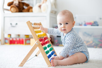 Cute little baby boy, playing with abacus at home
