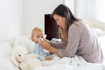 Mother and baby in pajamas, early in the morning, mom taking care of her sick toddler boy