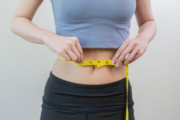 Workout, Slim asian young woman, girl standing, hand in measuring tape around waist her in fit sportswear on white background. Sport strong person in gym fitness for wellbeing, health and copy space.