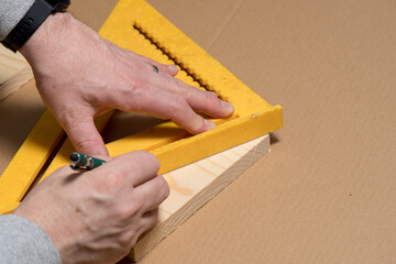 Carpenter using a pencil and old square marking a diagonal line on a wood board