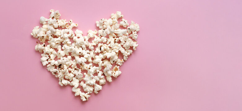 Pop Corn heart on pink background. Valentines day present cinema concept. Top view flat lay with copy space. Place for idea, quote or film title