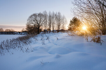 Winter landscape on frosty sunny morning. Sun's rays break through branches of trees. Everything is covered with snow
