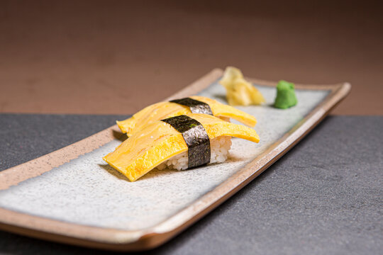 Tamagoyaki Sushi, sweet omelette wrap or Tamagoyaki, Japanese Omelette in a wooden plate. Front view with copy space.