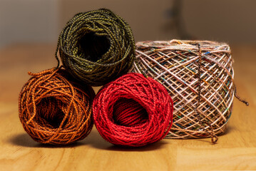 Obraz premium Multiple skeins balls of yarn with loose thread on wood table