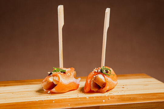 Front View of freshly prepared especial Sushi Roll with Salmon and Tuna on Top of wooden plate / Japanese Food. Copy space.