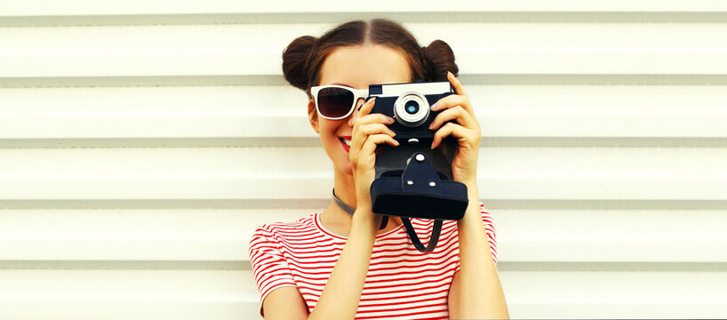 Portrait of happy smiling young woman photographer with vintage film camera, female with cool girly hairstyle on white background