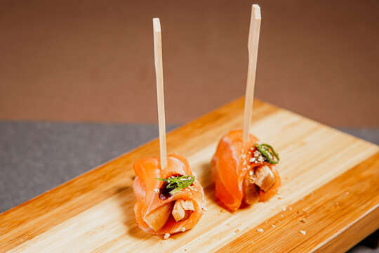 Front View of freshly prepared especial Sushi Roll with Salmon and Tuna on Top of wooden plate / Japanese Food. Copy space.