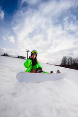 Young beautiful woman with a slim body in an erotic suit posing with a snowboard on a ski slope