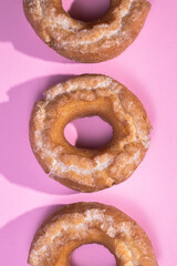 Row of glazed cake donuts on a pastel background