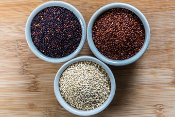 Red, black and white quinoa seeds on wooden background. Vegetarian food