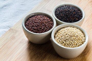 Red, black and white quinoa seeds on wooden background. Vegetarian food