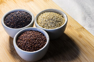 Red, black and white quinoa seeds on wooden background. Vegetarian food