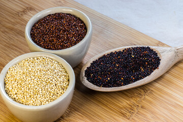Red, black and white quinoa seeds on wooden background. Vegetarian food