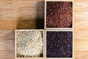 Red, black and white quinoa seeds on wooden background. Vegetarian food