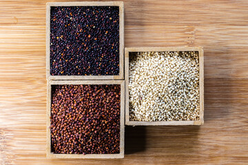 Red, black and white quinoa seeds on wooden background. Vegetarian food
