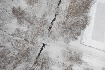 Road with a bridge over a ditch in the forest. There is a sports ground nearby. Snowy, winter...