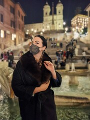 Portrait of a woman in a shiny mask against the backdrop of the Spanish steps in Rome
