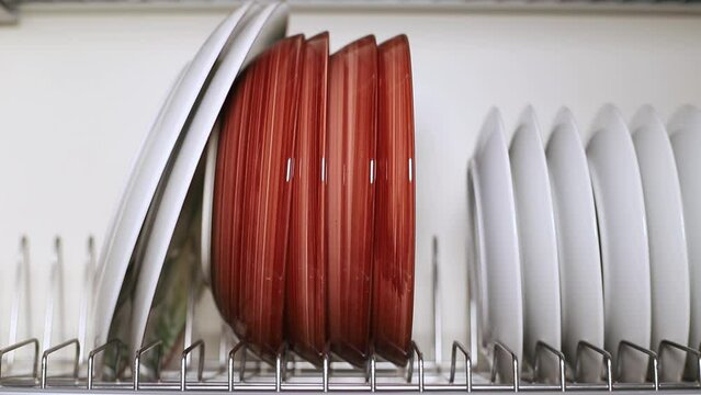 A set of dishes is dried and placed on a metal stand in the kitchen cabinet