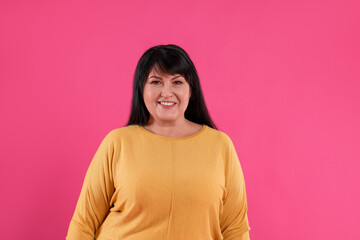 Fototapeta premium Beautiful overweight mature woman with charming smile on pink background