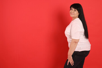 Obraz premium Beautiful overweight mature woman with charming smile on red background. Space for text