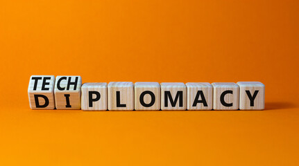 Diplomacy or techplomacy symbol. Turned wooden cubes and changed the concept word diplomacy to techplomacy. Beautiful orange background, copy space. Business, diplomacy or techplomacy concept.