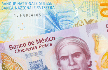 Fototapeta premium A macro image of a pink, plastic fifty peso bank note from Mexico paired up with a yellow Swiss ten franc bill. Shot close up in macro.