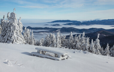 Snowy bench at mountain with spectacular view of Eastern Carpathians in winter.