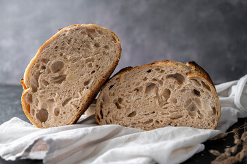 Sourdough artisan homemade bread sliced in halfs on dark background.