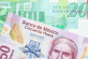 Fototapeta premium A macro image of a pink, plastic fifty peso bank note from Mexico paired up with a green and white twenty shekel bill from Israel. Shot close up in macro.