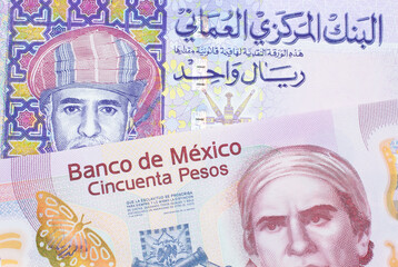 A macro image of a pink, plastic fifty peso bank note from Mexico paired up with a colorful one rial note note from Oman.  Shot close up in macro.