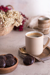 Beautiful cup of coffee on wooden table with chocolate cookies. pastel tone. Vertical