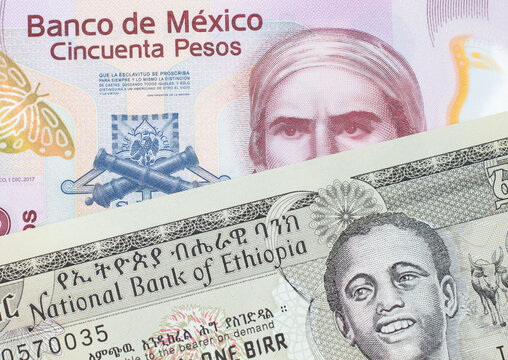 A macro image of a pink, plastic fifty peso bank note from Mexico paired up with a grey Ethiopian one birr bill.  Shot close up in macro.