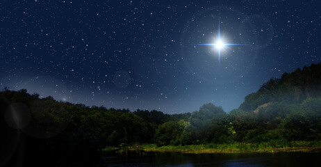 Bright star indicates the Nativity of Jesus Christ in the starry sky. Fog is rising over the night forest.